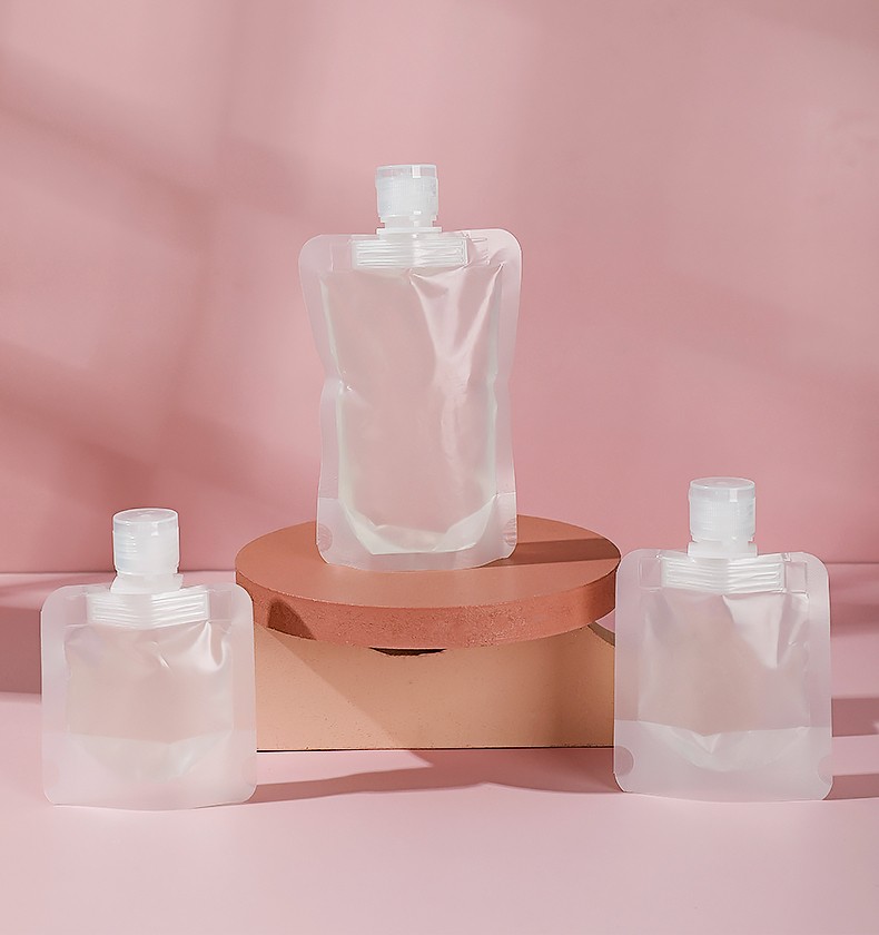 Three translucent spout pouches displayed on a terracotta pedestal against a pink studio backdrop